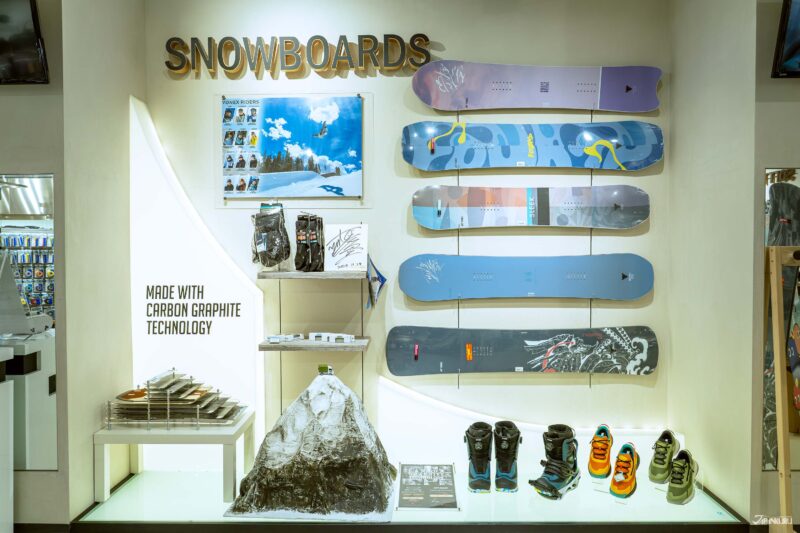 สโนว์บอร์ดและรองเท้าปีนเขาเรียงรายอยู่บนผนังและชั้นวางภายในร้าน