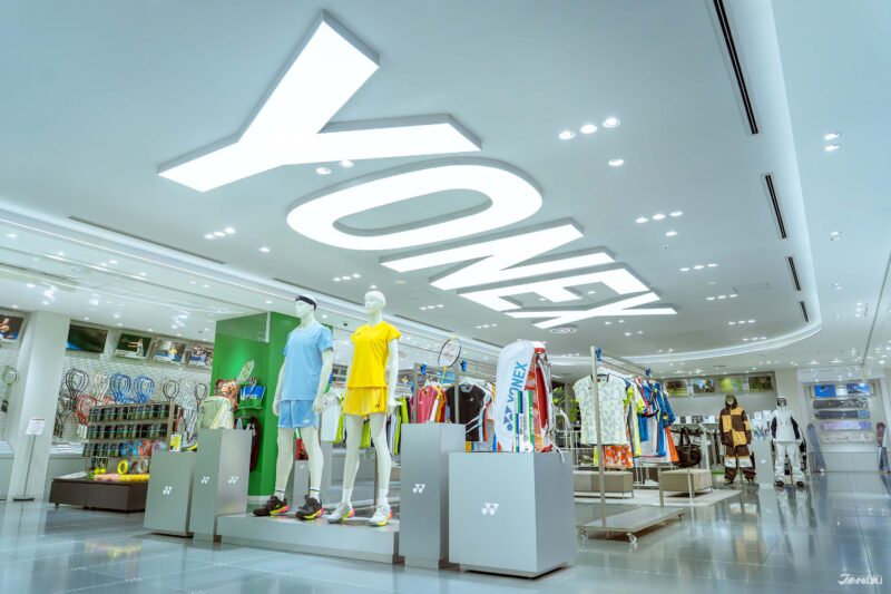 ภายในโชว์รูมโอซาก้า เรียงรายด้วยชุดและอุปกรณ์กีฬา บนเพดานประดับคำว่าโยเน็กซ์